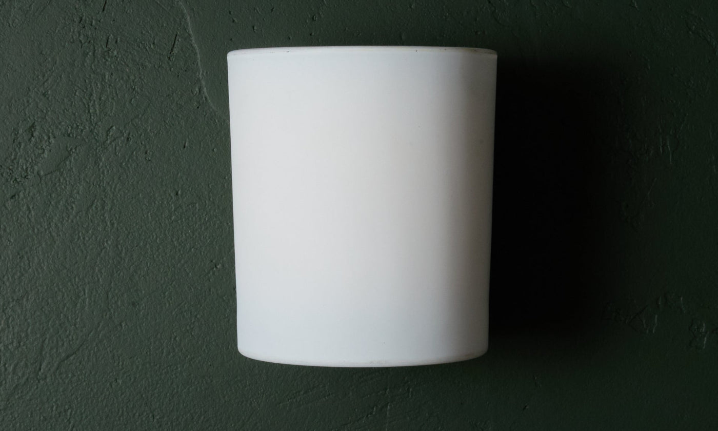 White cylindrical wall light fixture on a dark green wall