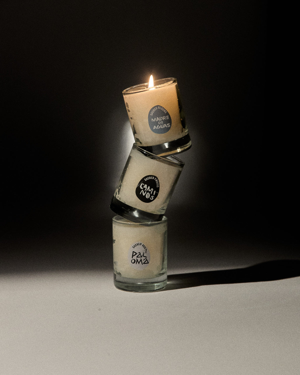 Three stacked glass candle holders with lit candles on a dark background