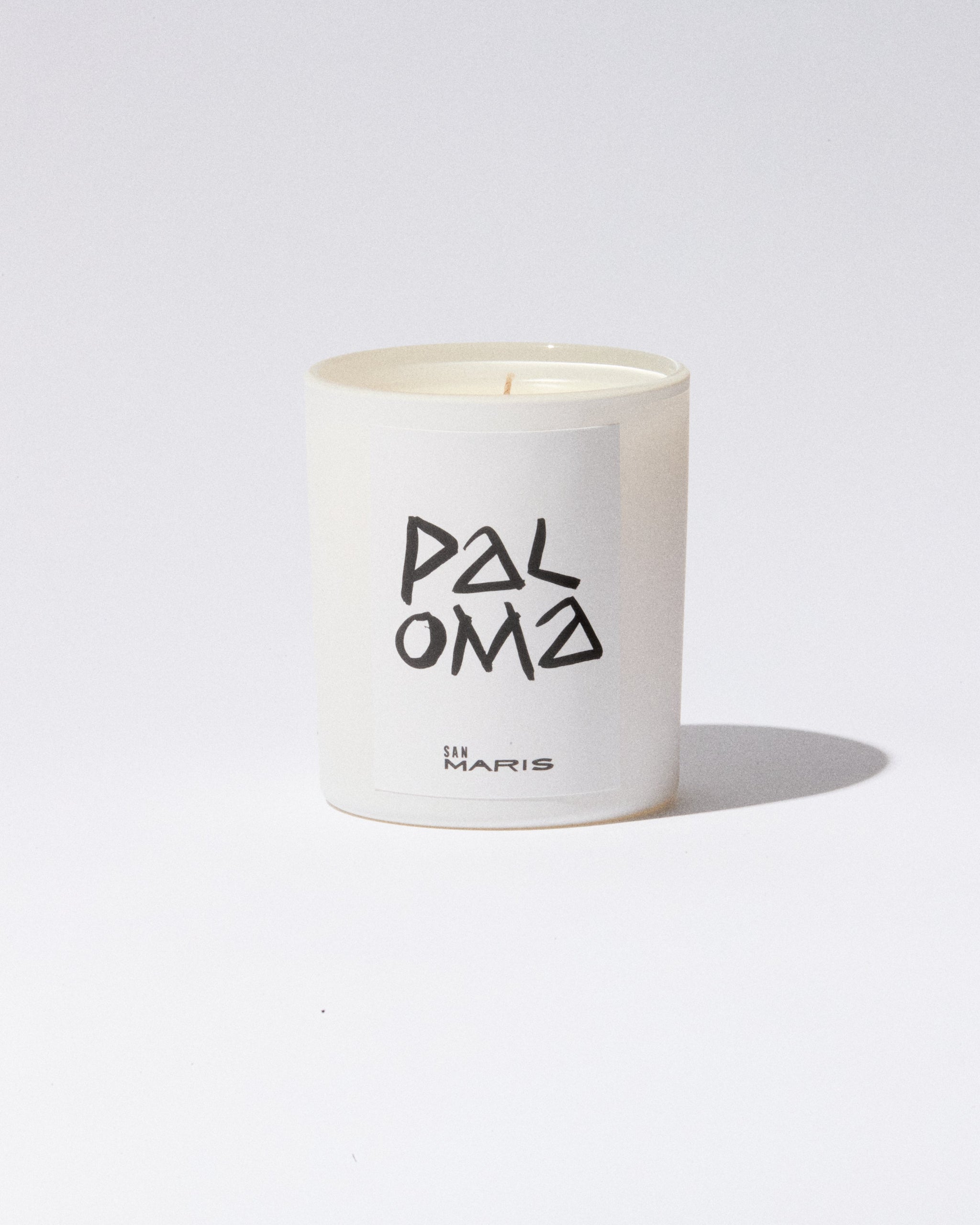 White candle with 'PALOMA' and 'San MARiS' text on a white background