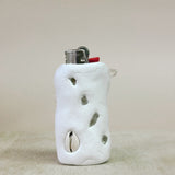 White ceramic lighter holder with embedded stones on a beige background