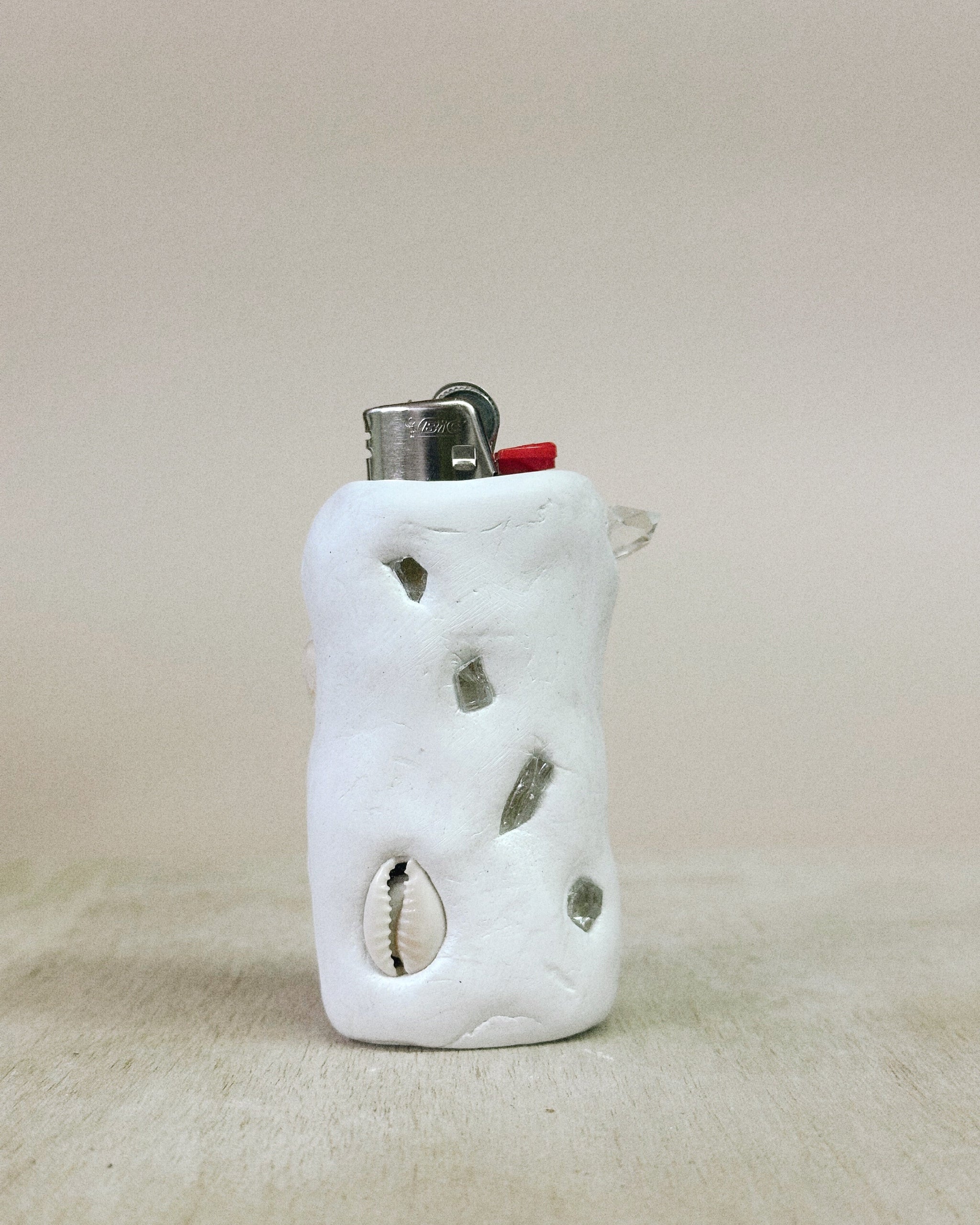 White ceramic lighter holder with embedded stones on a beige background