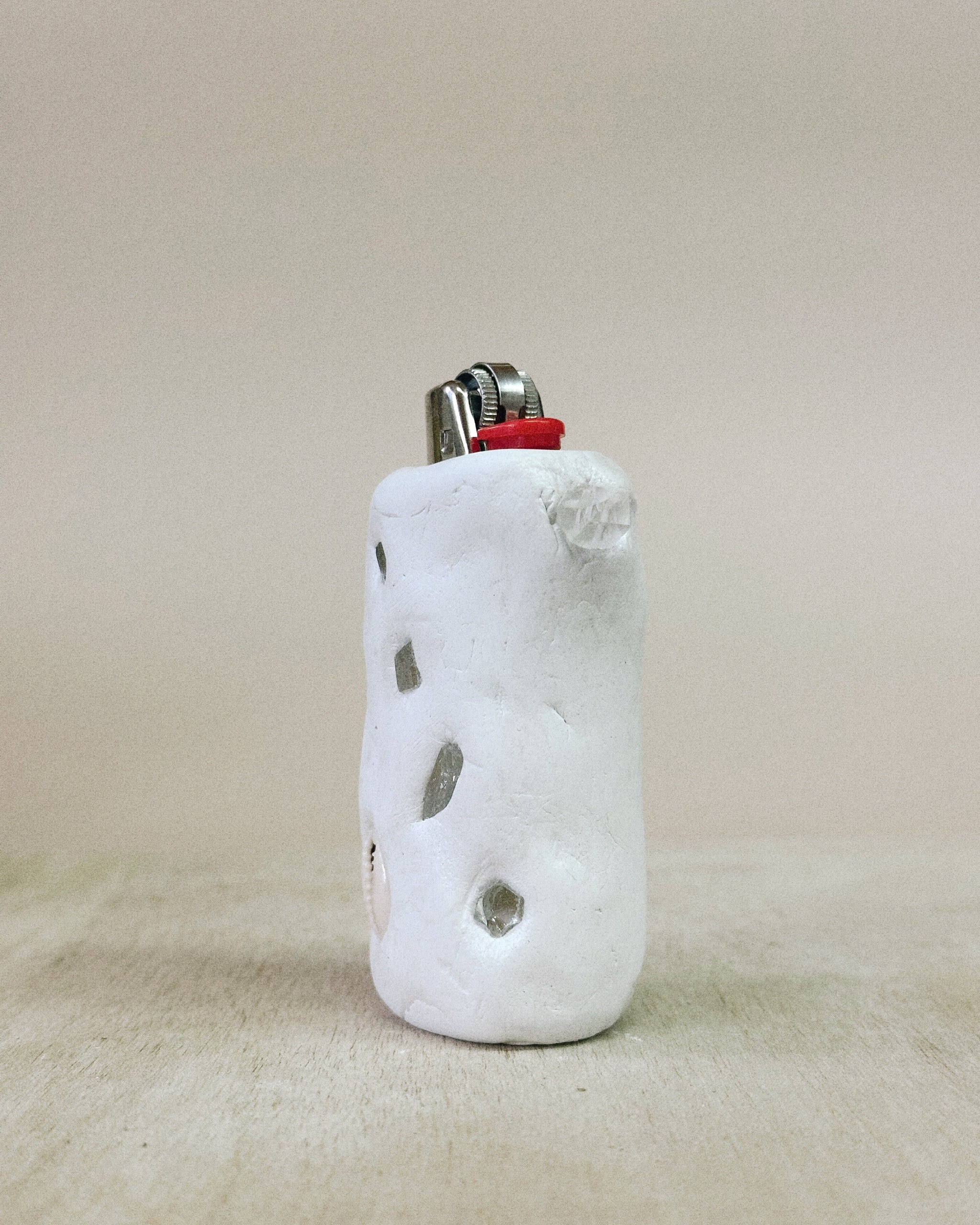 White ceramic lighter holder with textured surface on a beige background