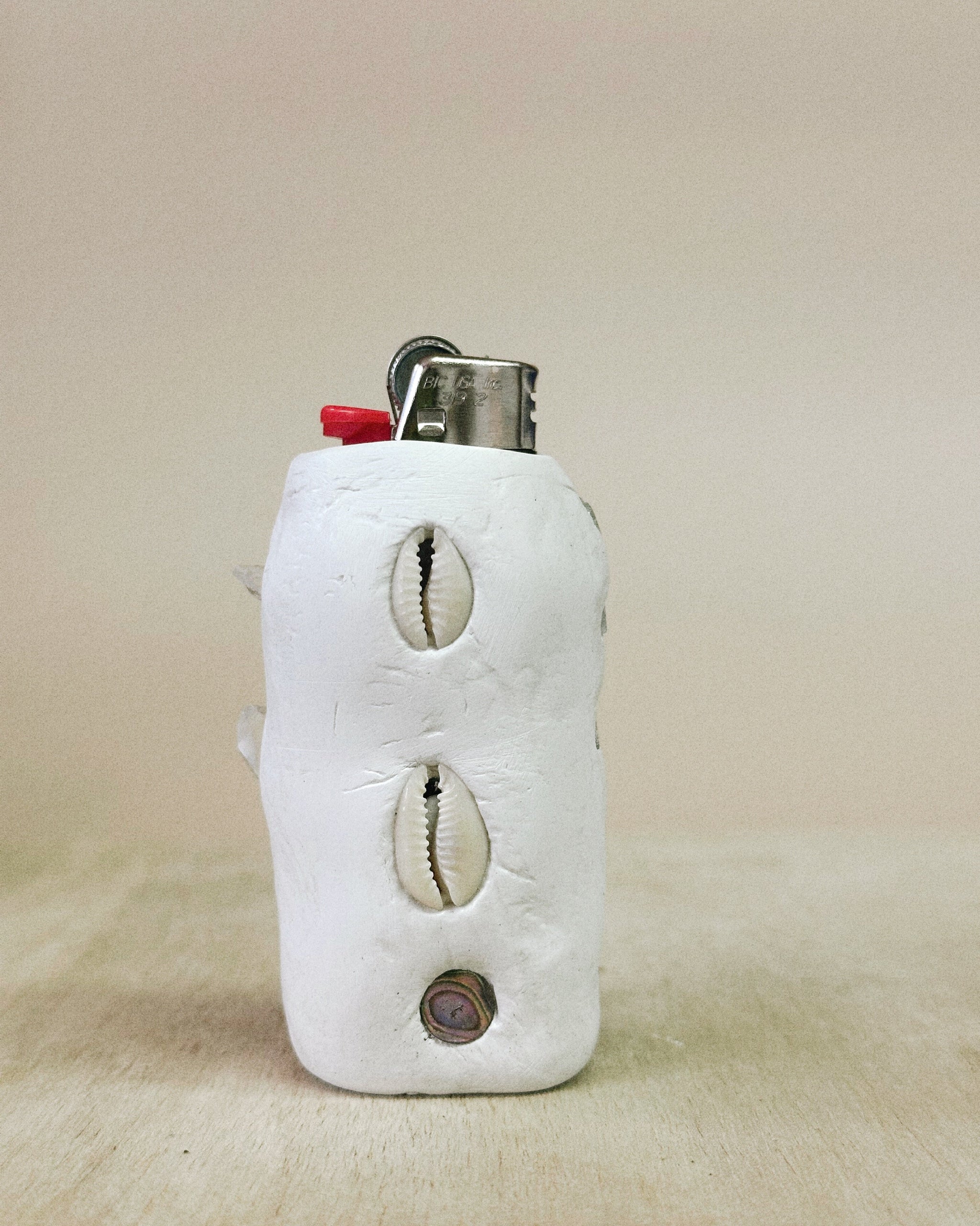 Lighter with cowrie shell designs on a beige background