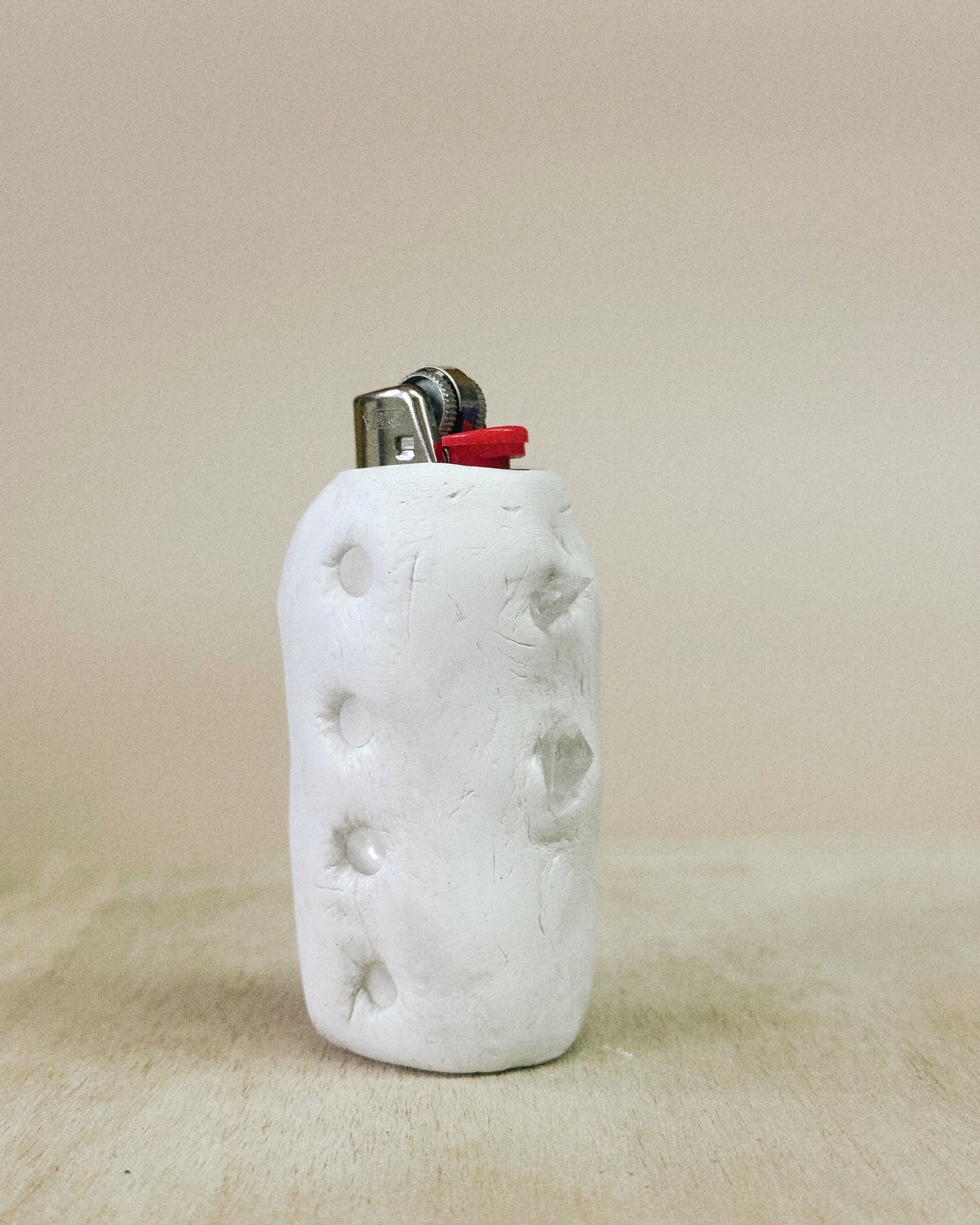 White textured lighter case with a red accent on a beige background