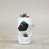 White ceramic lighter with embedded stones on a beige surface