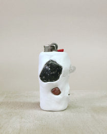 White ceramic lighter with embedded stones on a beige surface