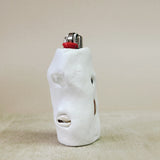 White ceramic face sculpture lighter on a beige surface