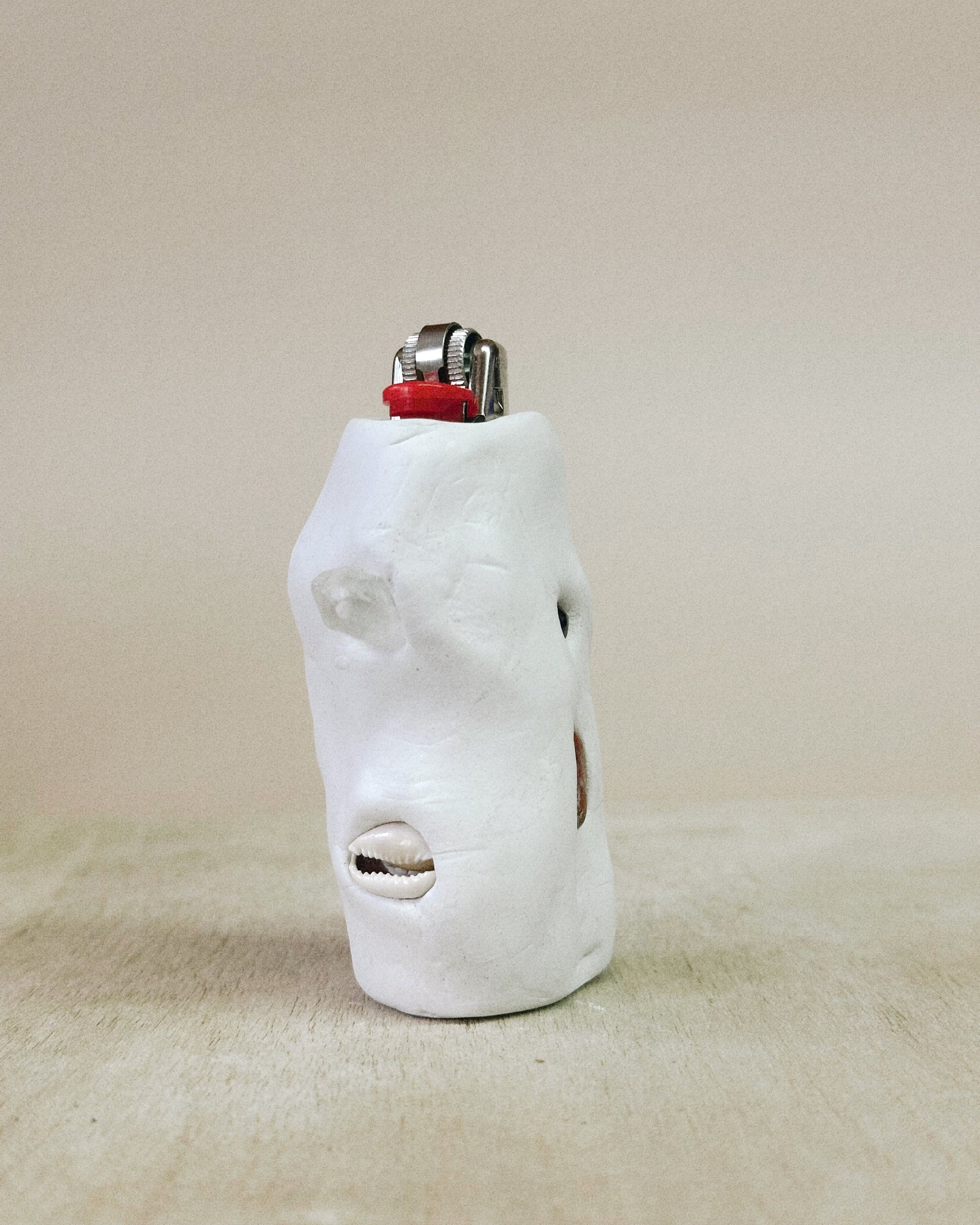White ceramic face sculpture lighter on a beige surface
