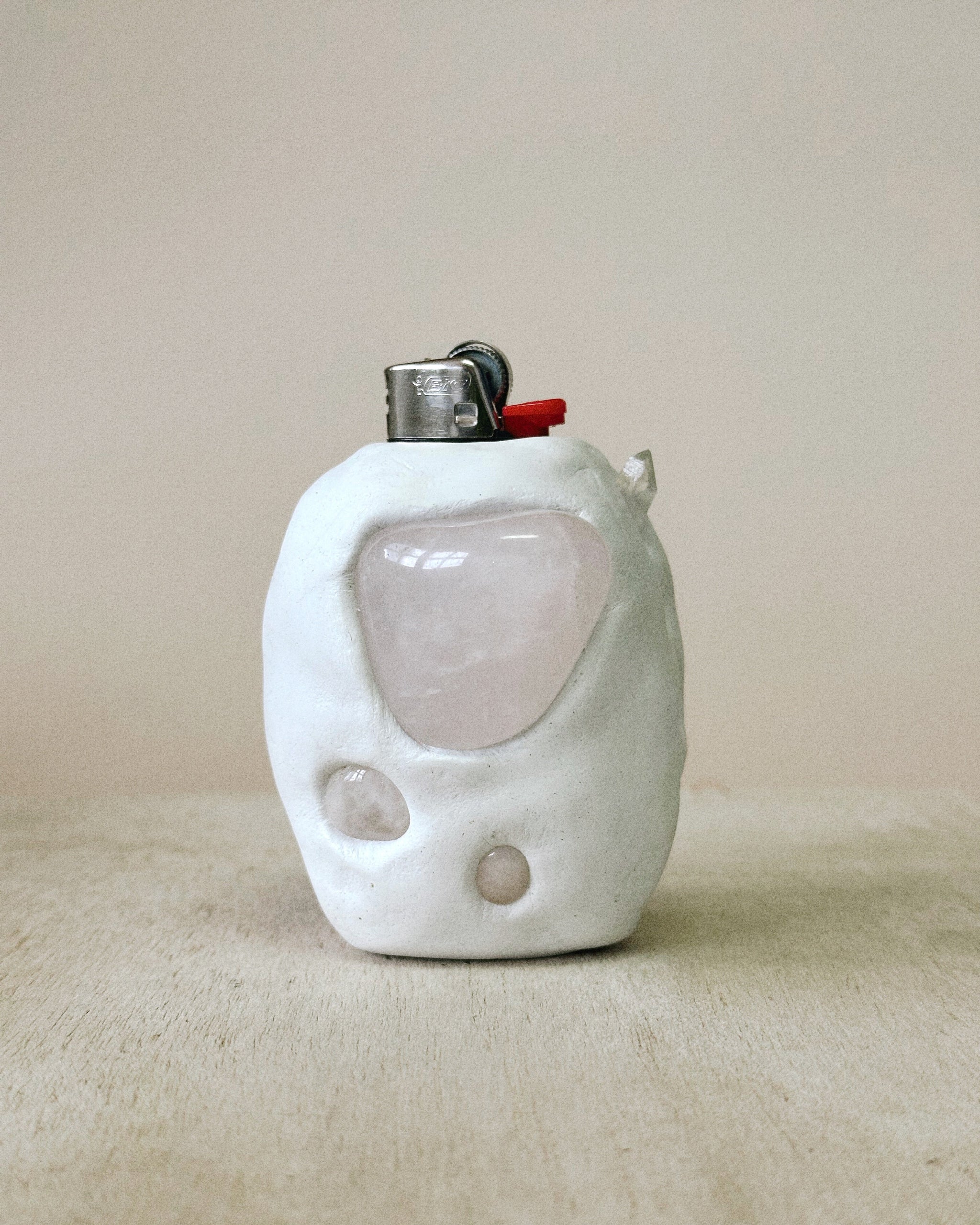 White ceramic lighter on beige back drop with Rose Quartz