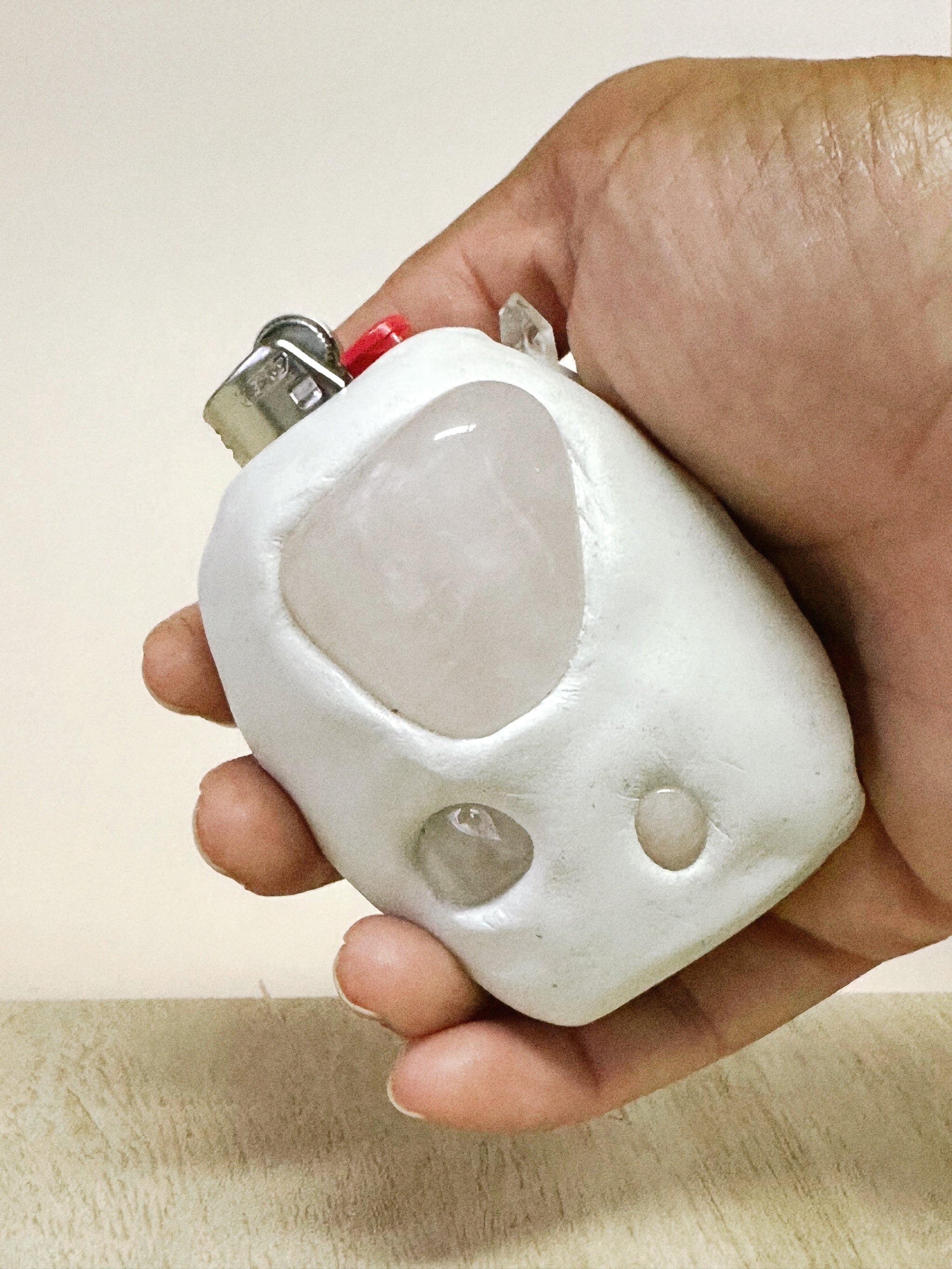 Hand holding a white lighter with a beige background