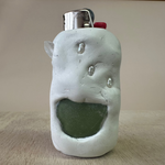 White ceramic face-shaped object with a green interior on a beige surface