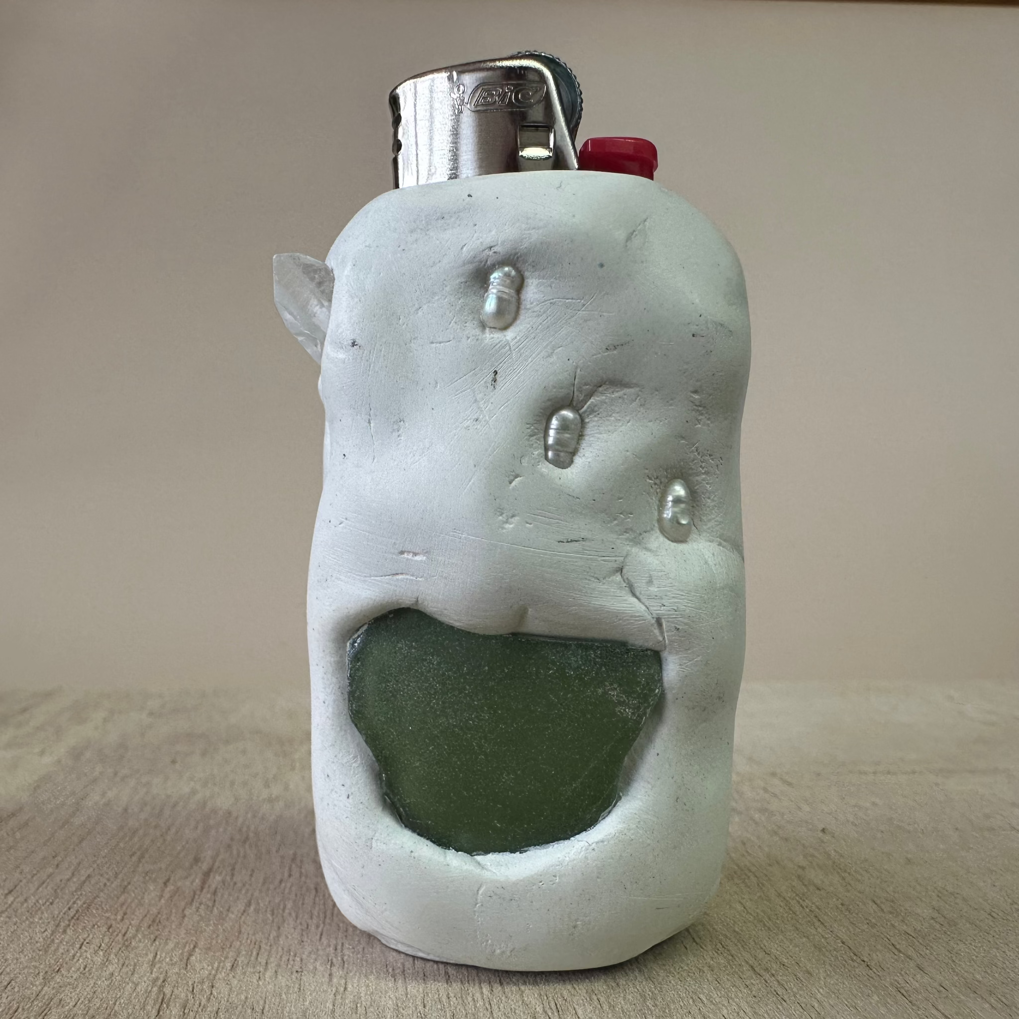 White ceramic face-shaped object with a green interior on a beige surface
