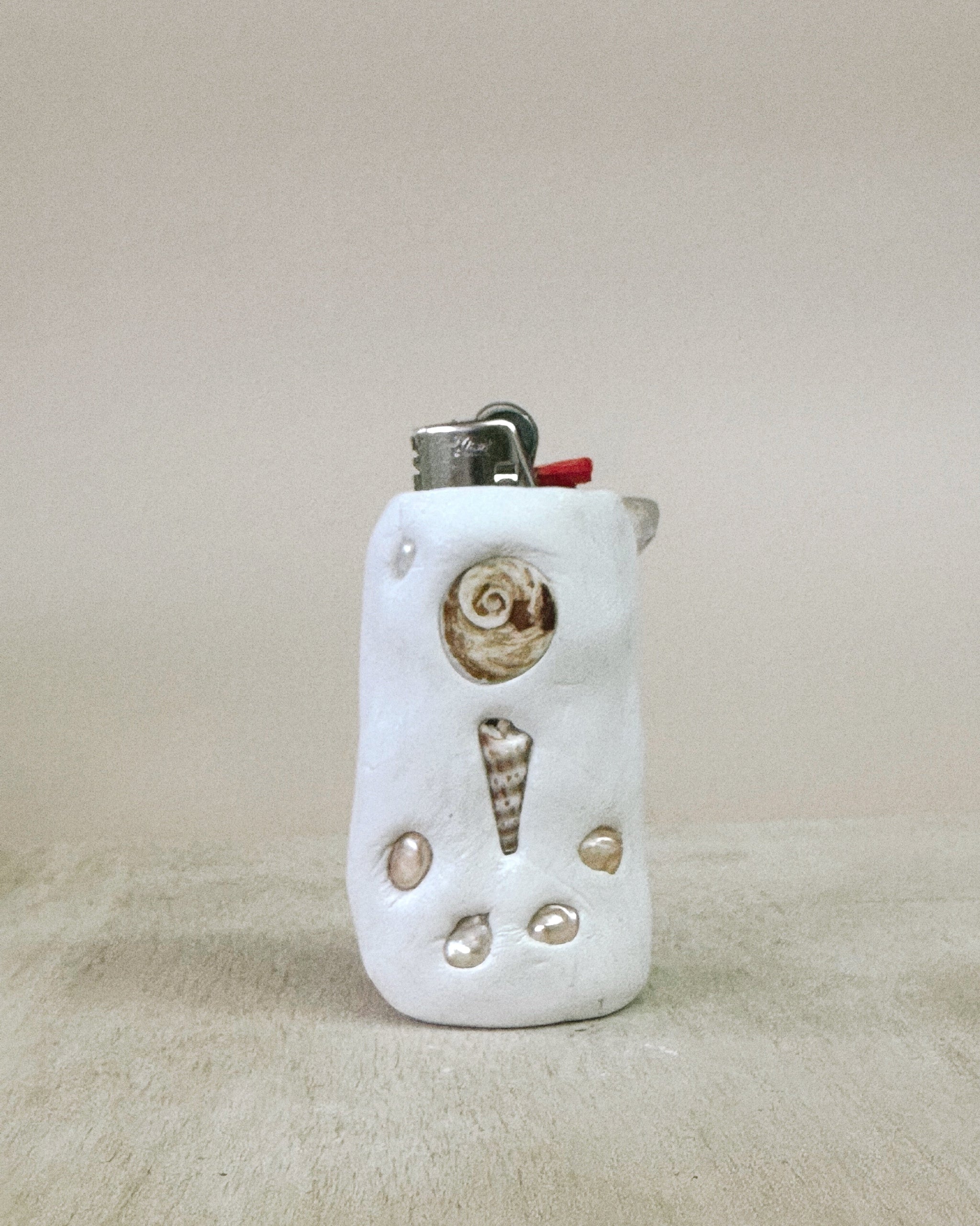 Lighter with shell decorations on a beige background