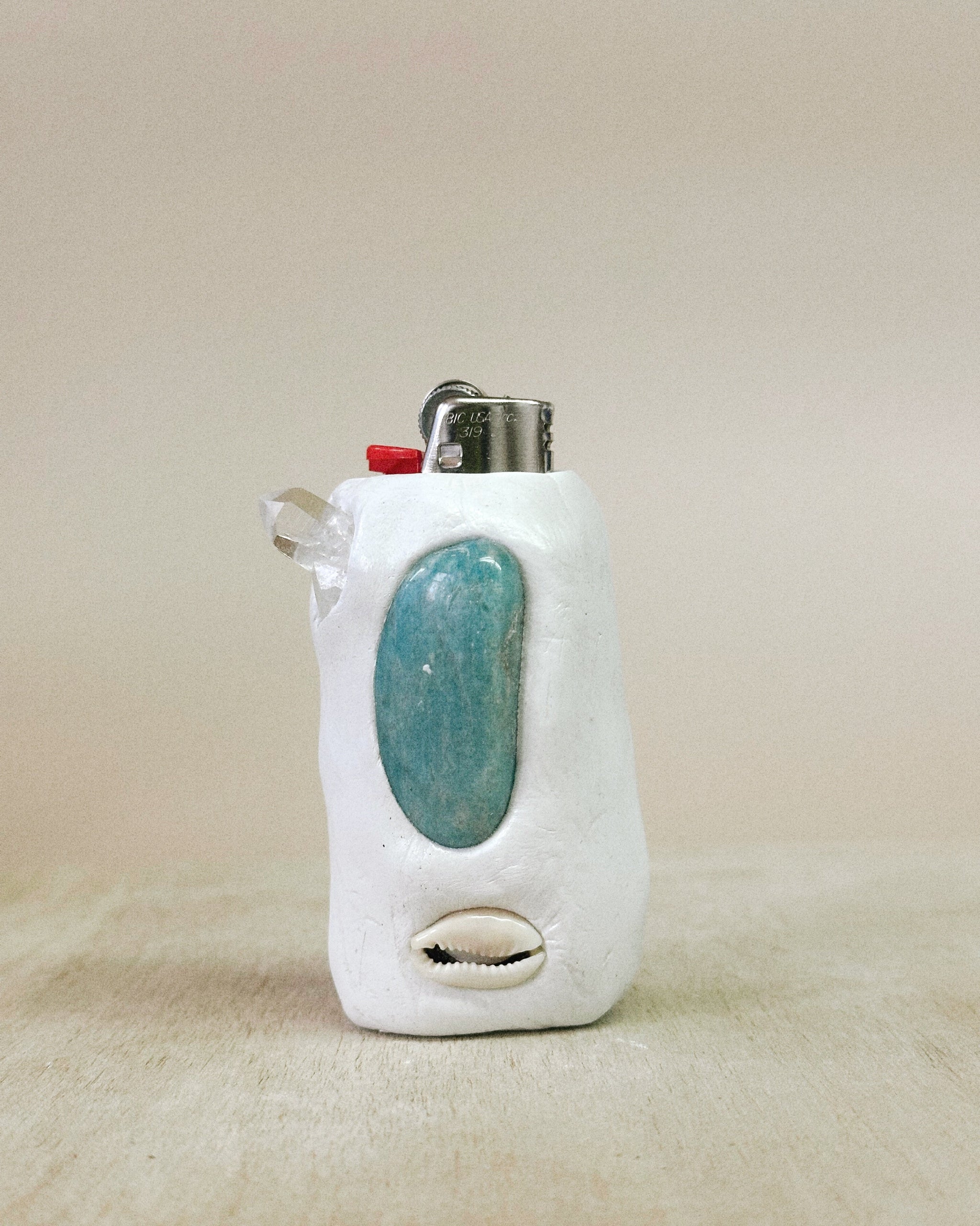 Lighter with a turquoise stone in a white holder on a beige background