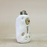 White ceramic lighter with decorative elements on a beige background