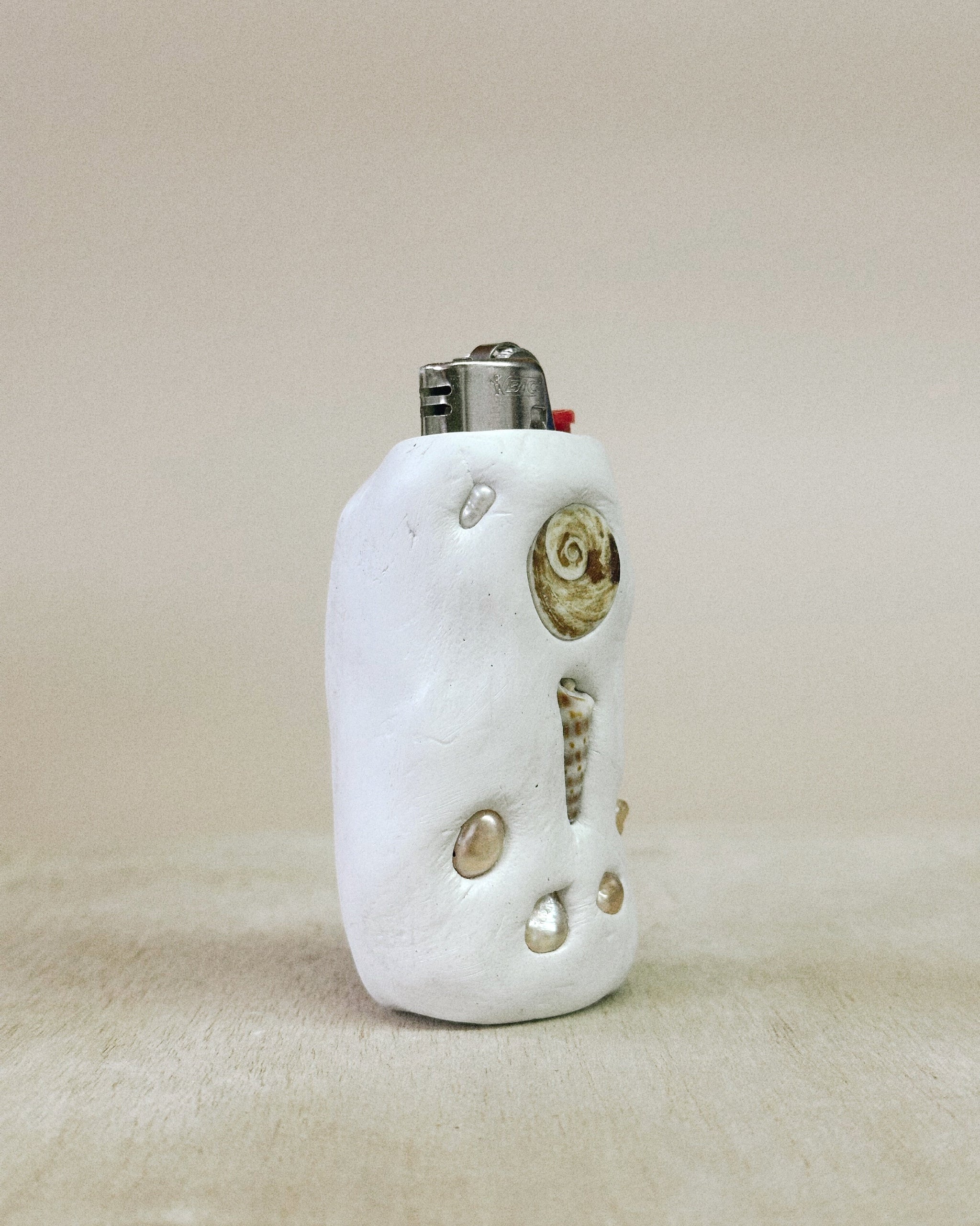 White ceramic lighter with decorative elements on a beige background