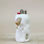 Marble-textured lighter case with embedded stones on a beige surface