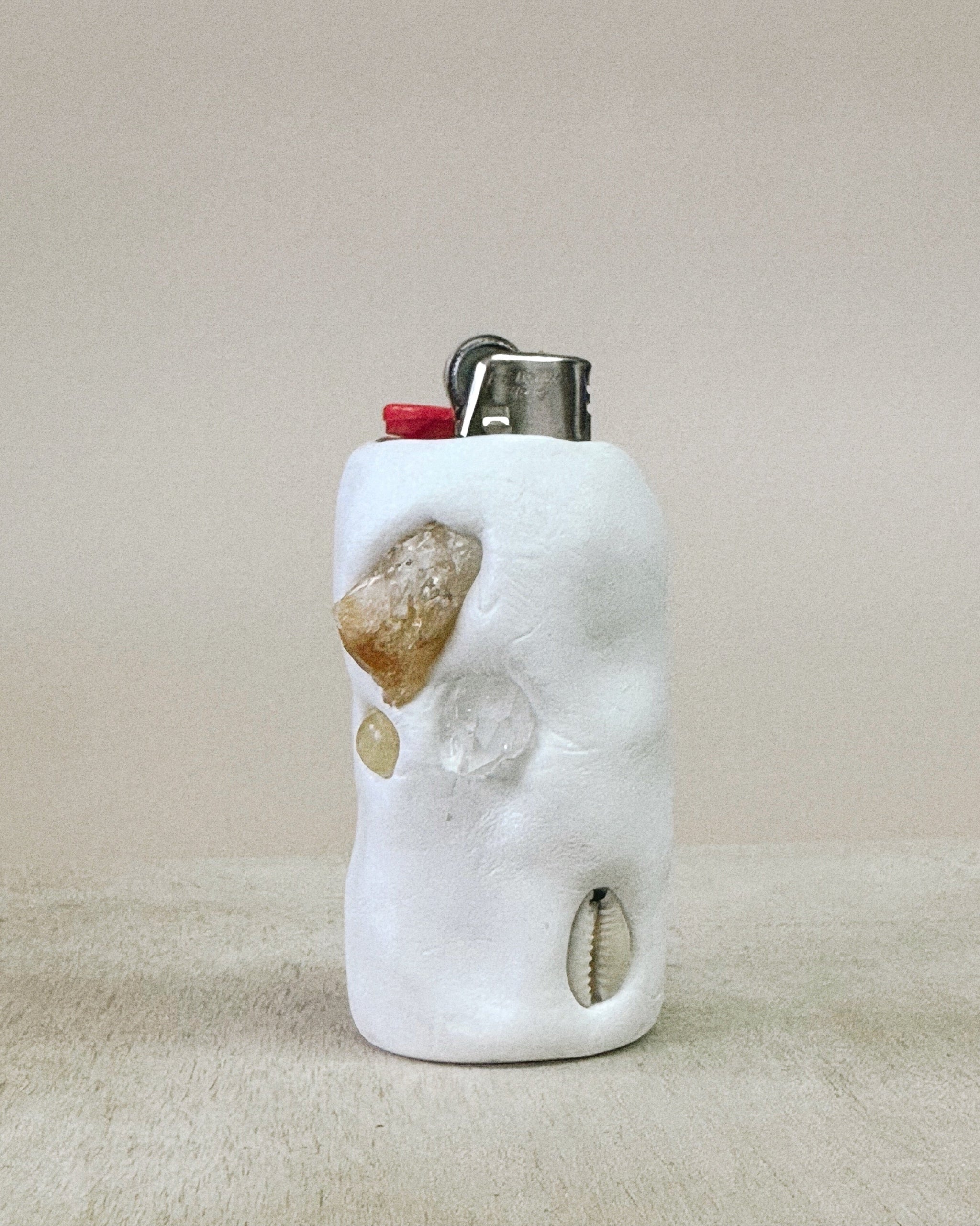Marble-textured lighter case with embedded stones on a beige surface