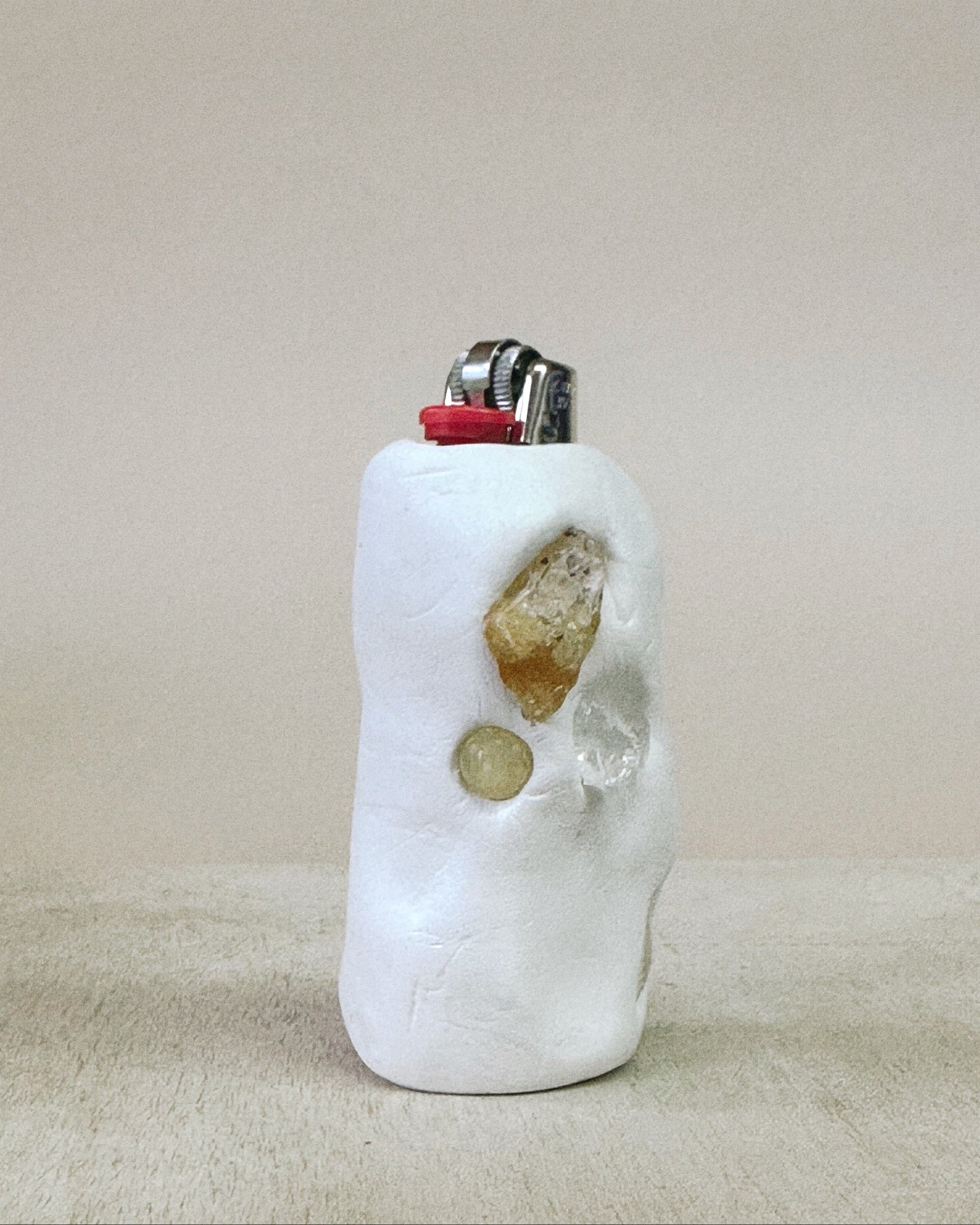 Lighter with decorative stones on a beige surface