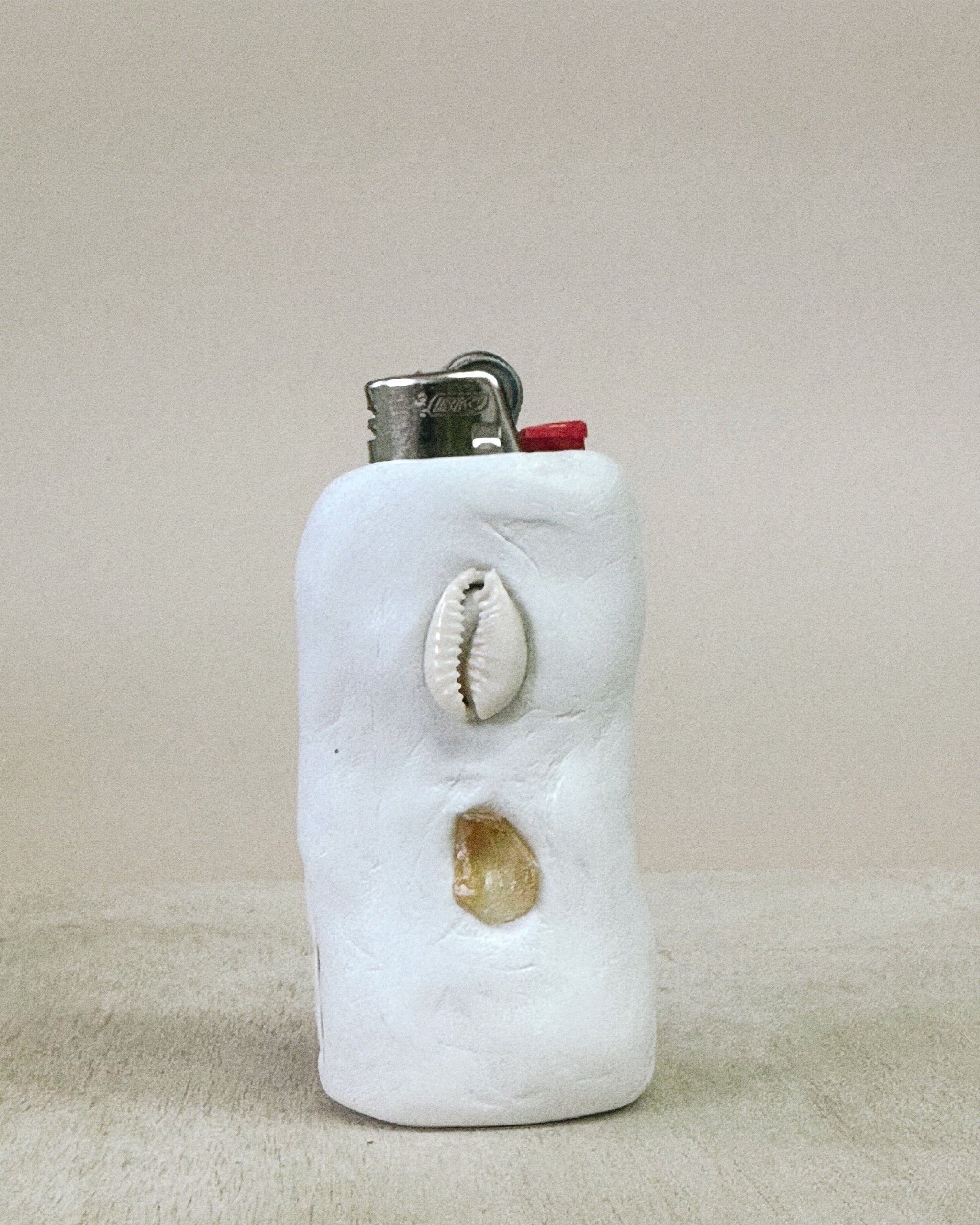 Lighter case with shells on a beige background