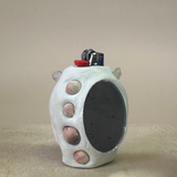 Ceramic lighter with textured surface and small stones on a beige background