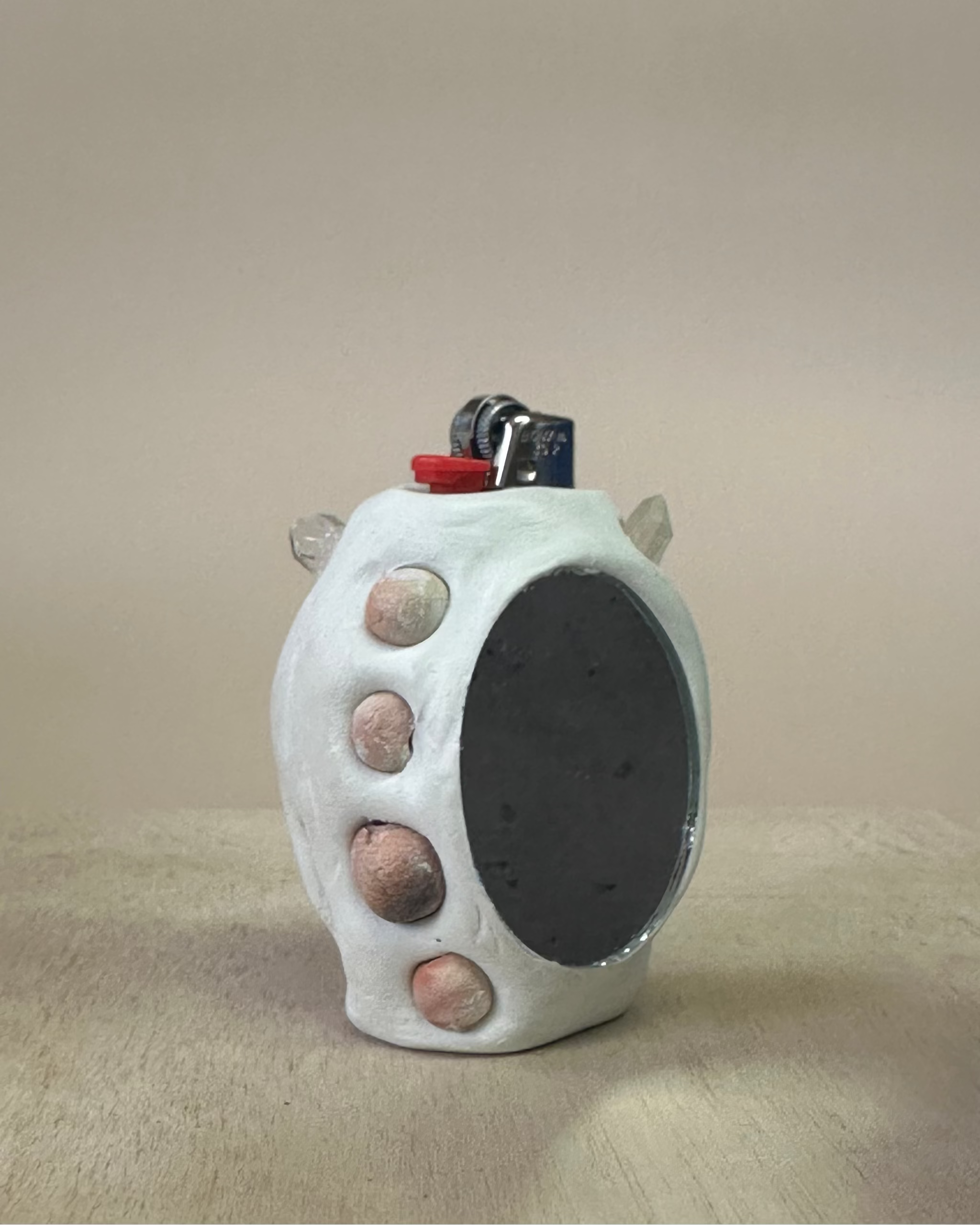 Ceramic lighter with textured surface and small stones on a beige background