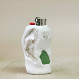 White ceramic shaped object  lighter with a green glass lighter on a beige background