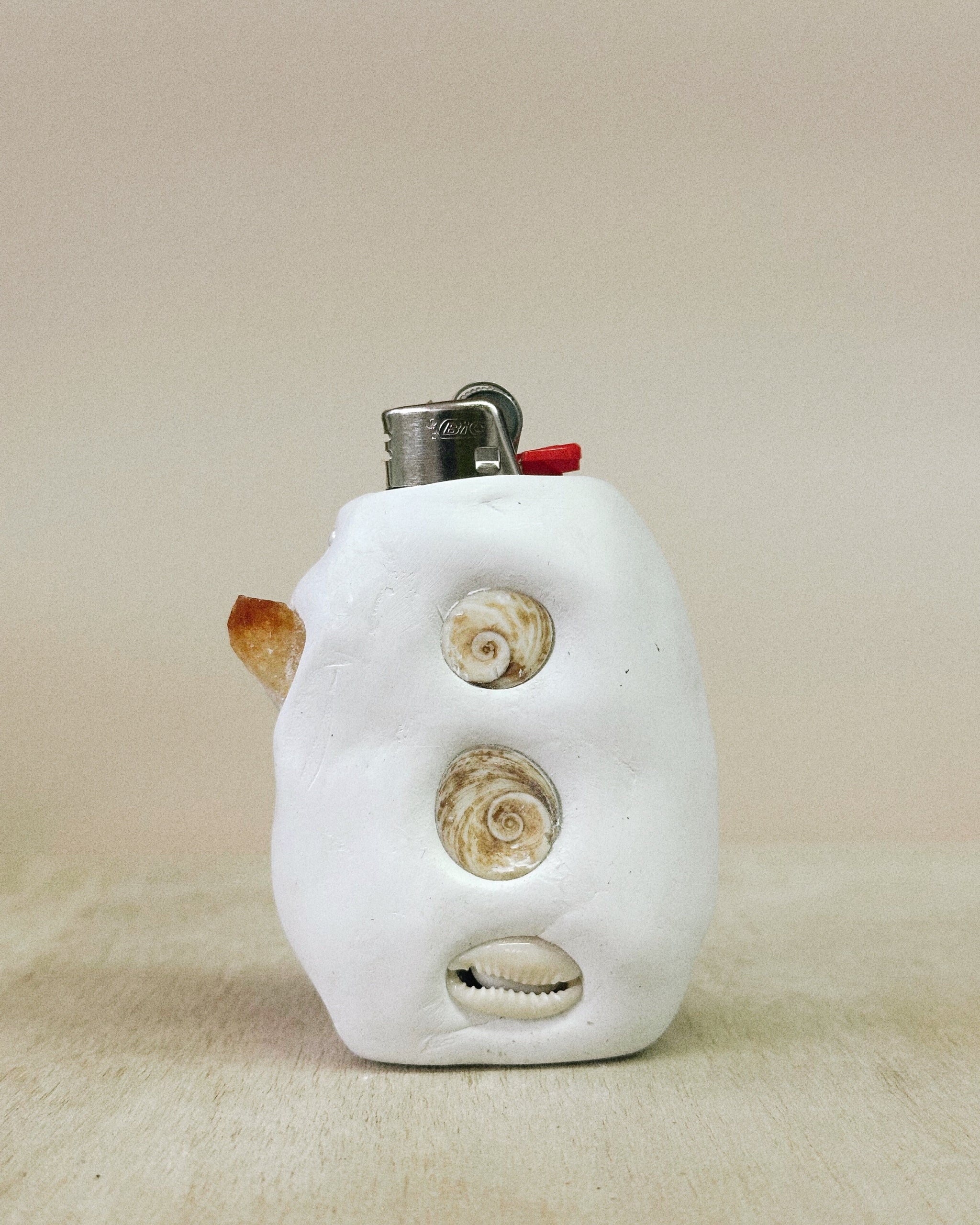 White ceramic lighter with shell designs on a beige background