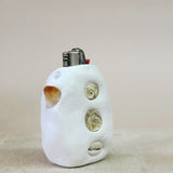 White ceramic lighter with shell designs on a beige background