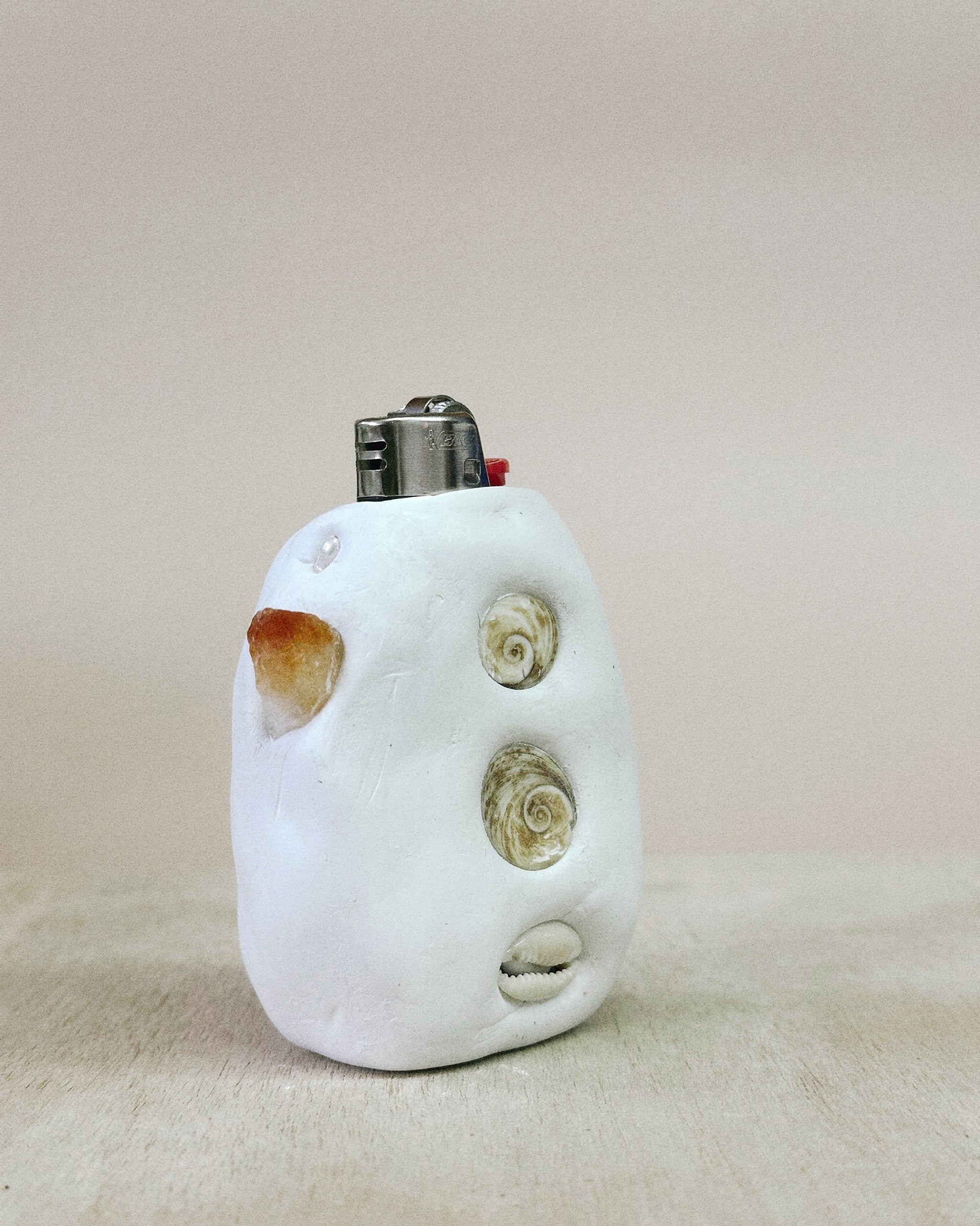 White ceramic lighter with shell designs on a beige background