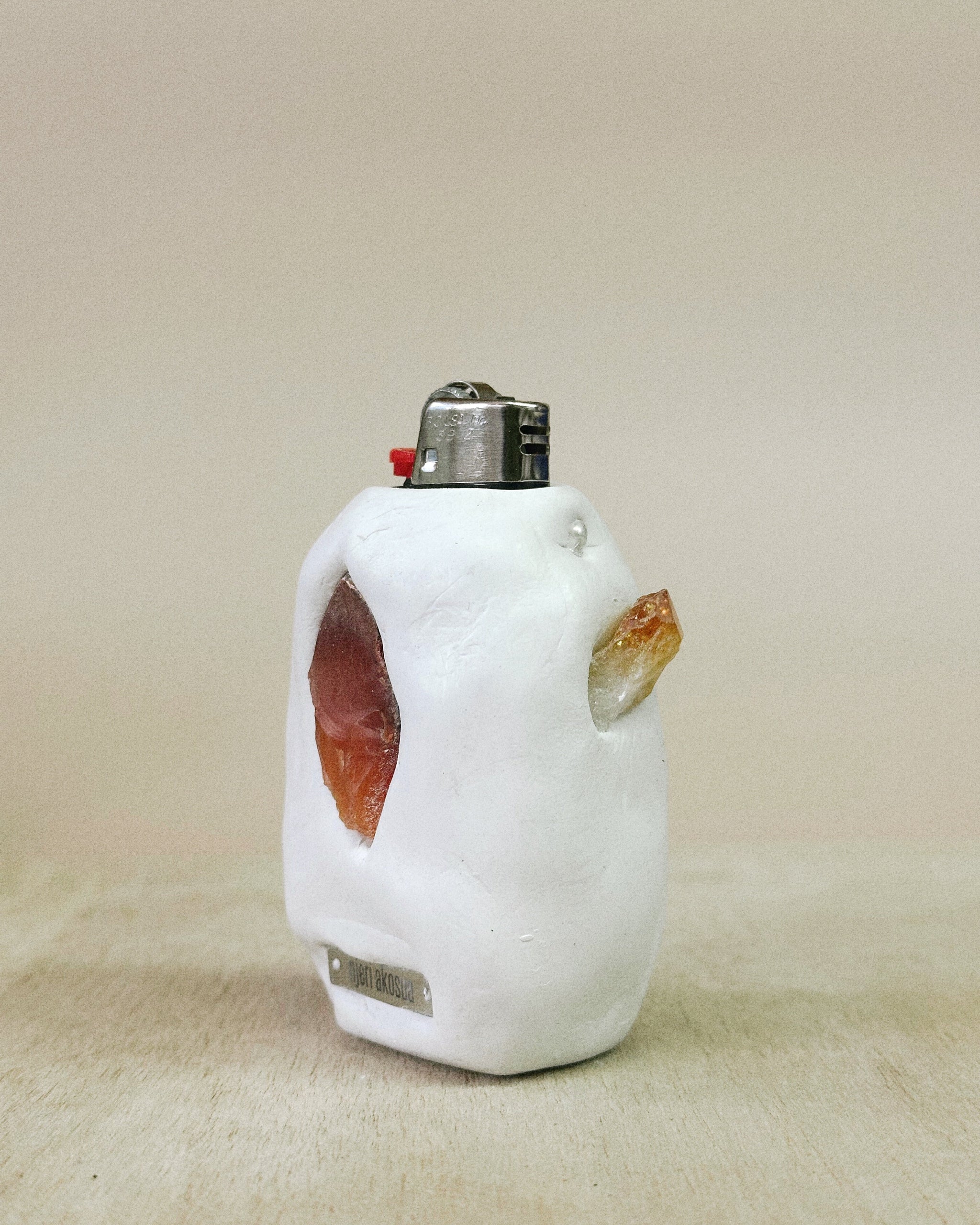 White ceramic lighter case with decorative elements on a beige background