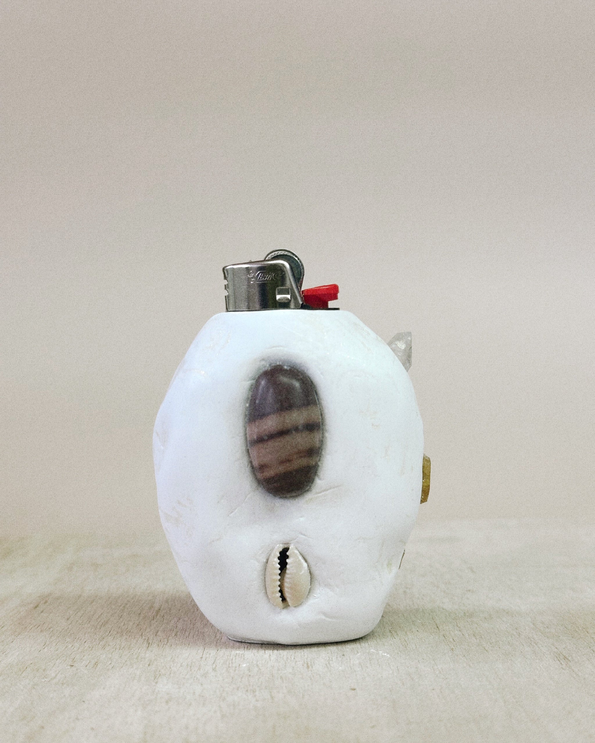 White lighter with a shell design on a beige background