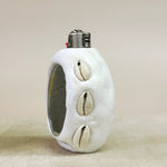  White lighter with shell designs and mirror on a beige background