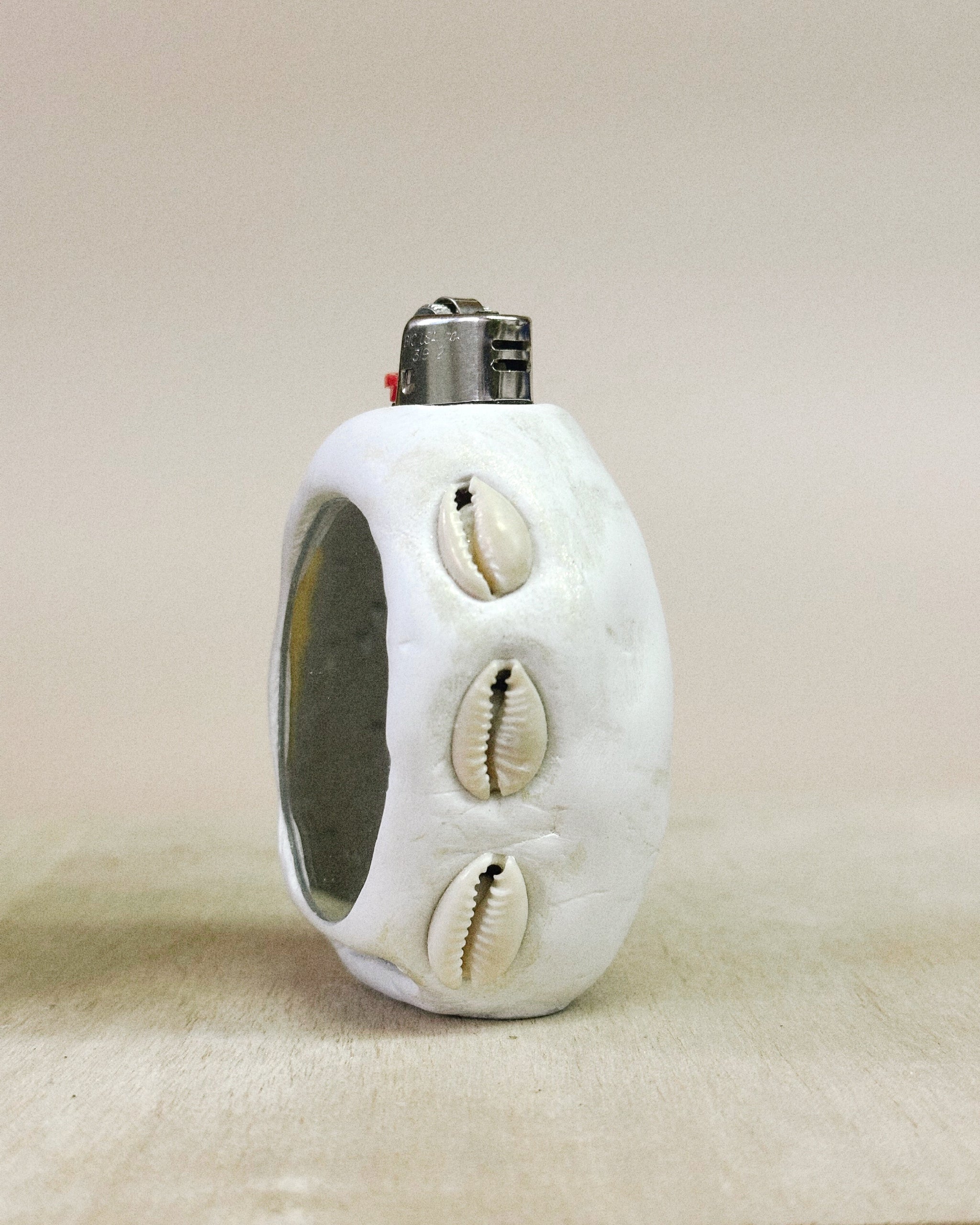  White lighter with shell designs and mirror on a beige background