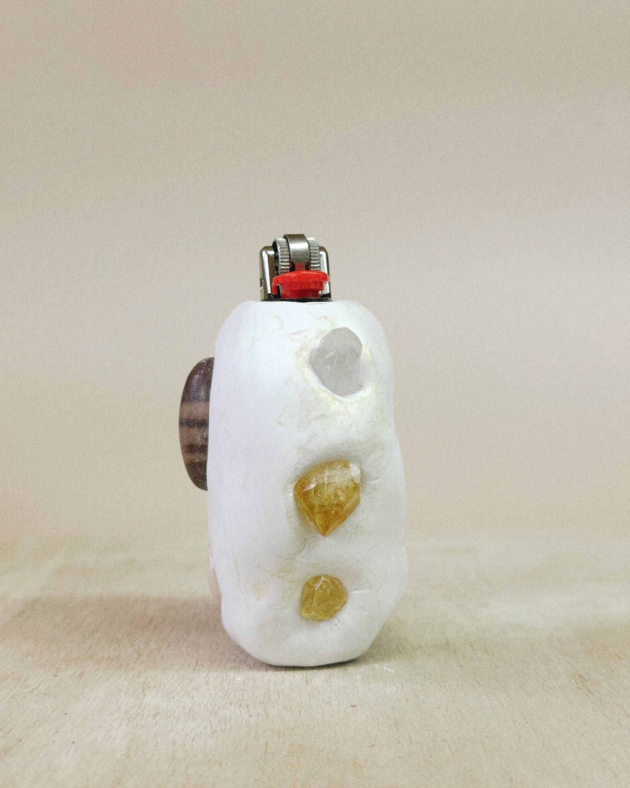 White stone lighter with citrineinclusions on a beige background