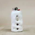 White ceramic lighter case with decorative elements on a beige background