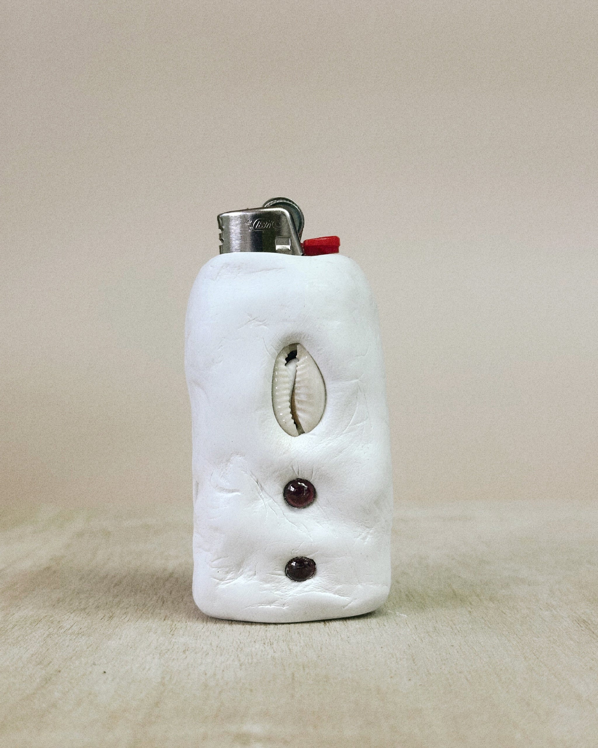 White ceramic lighter case with decorative elements on a beige background