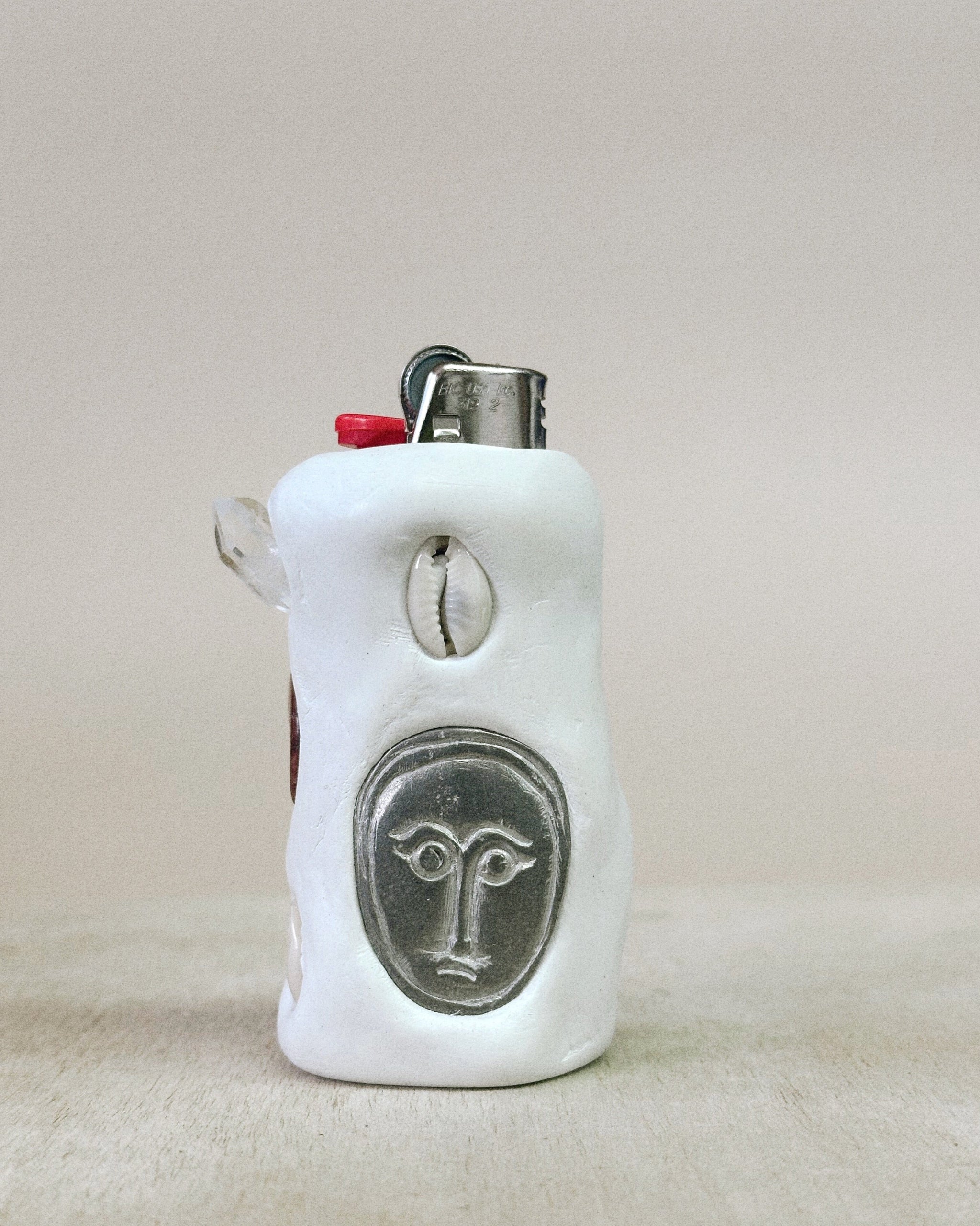 White ceramic lighter with face design on a beige surface
