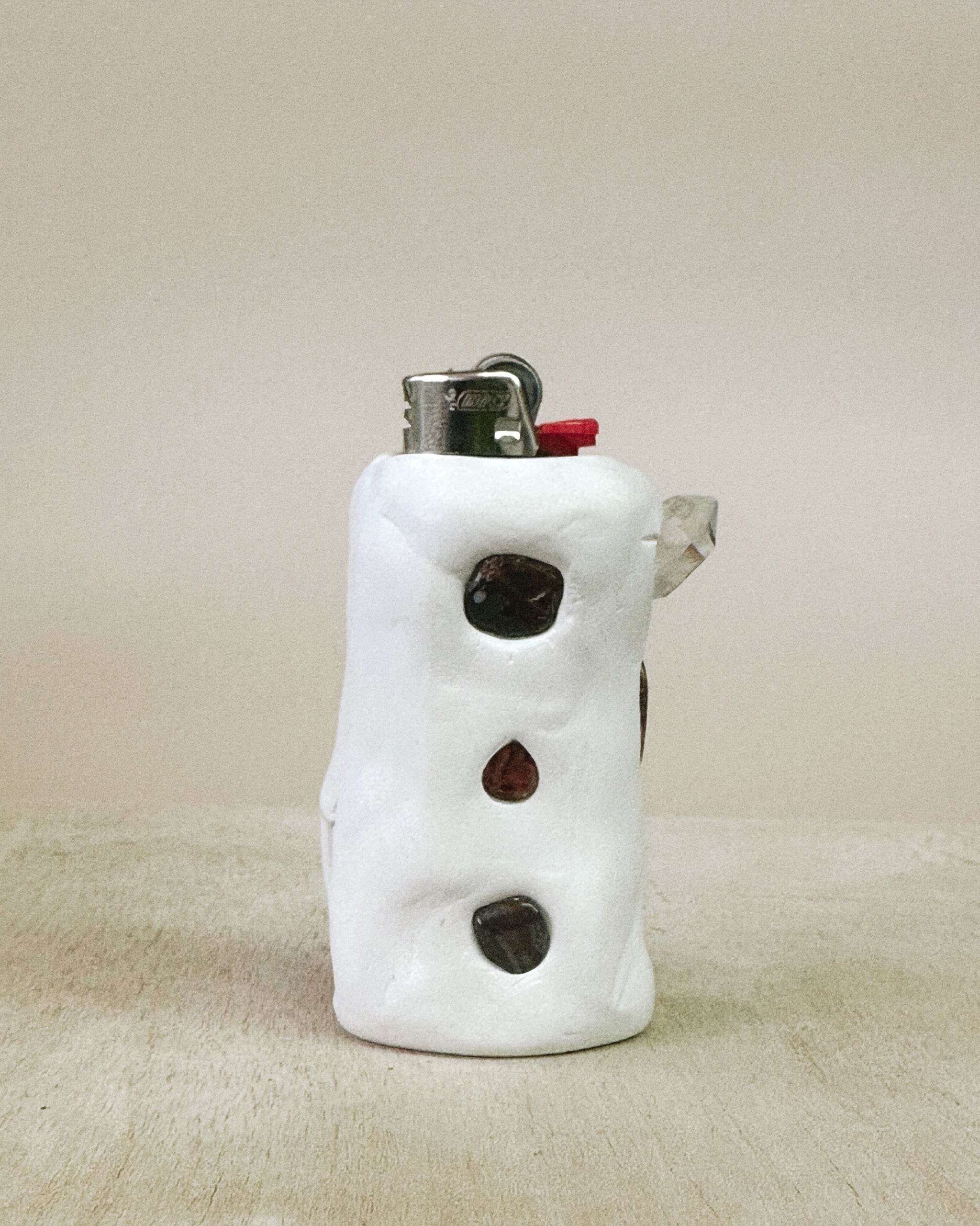 White ceramic lighter with black and red accents on a beige surface