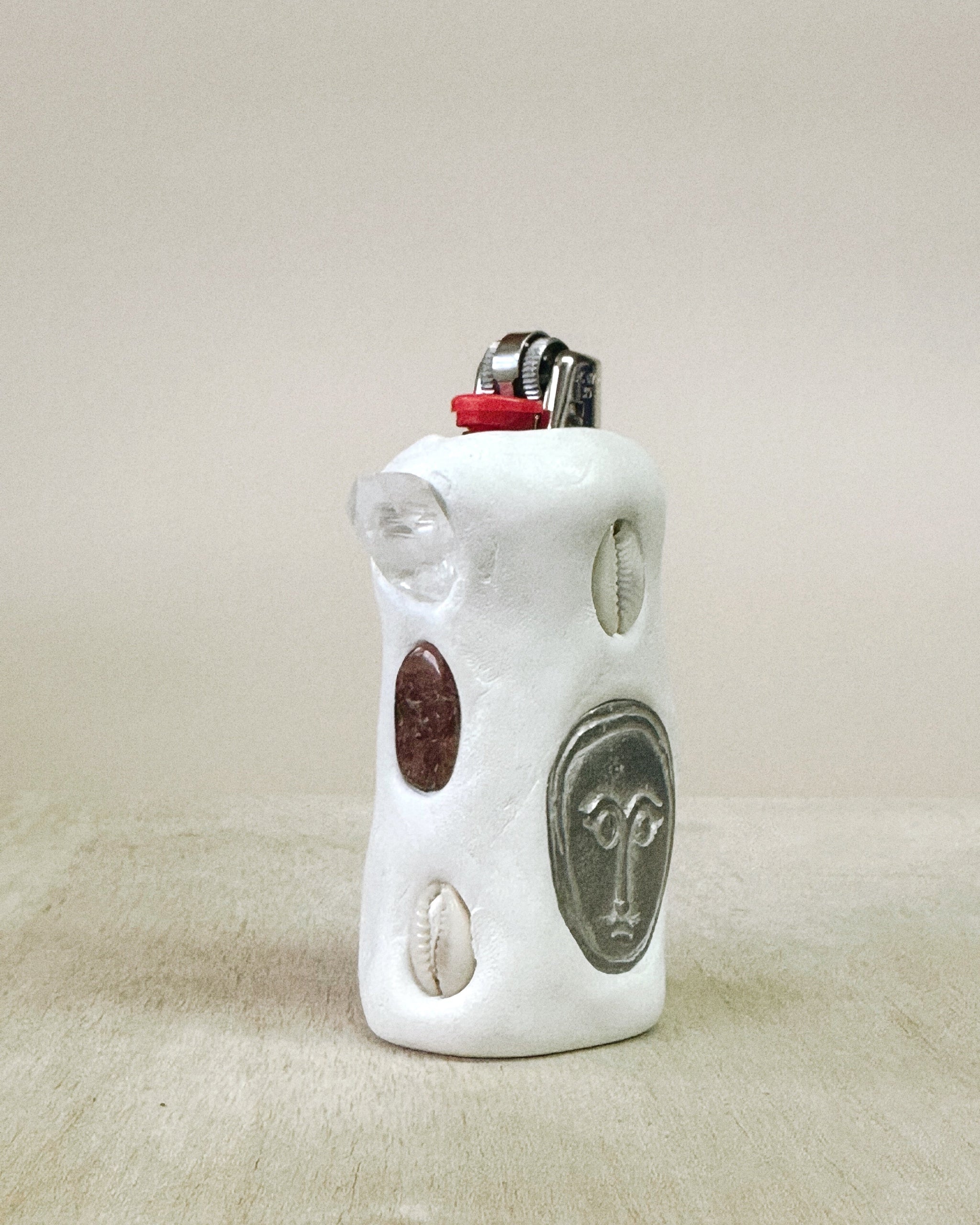 White ceramic lighter with decorative elements on a beige background