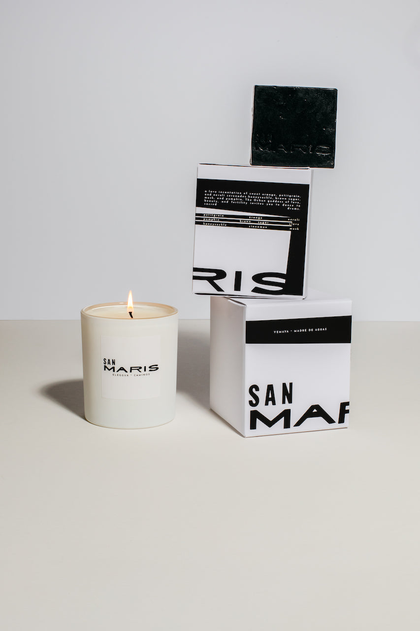 Best selling San Maris products staked vertical with a Lit Caminos candle beside it 