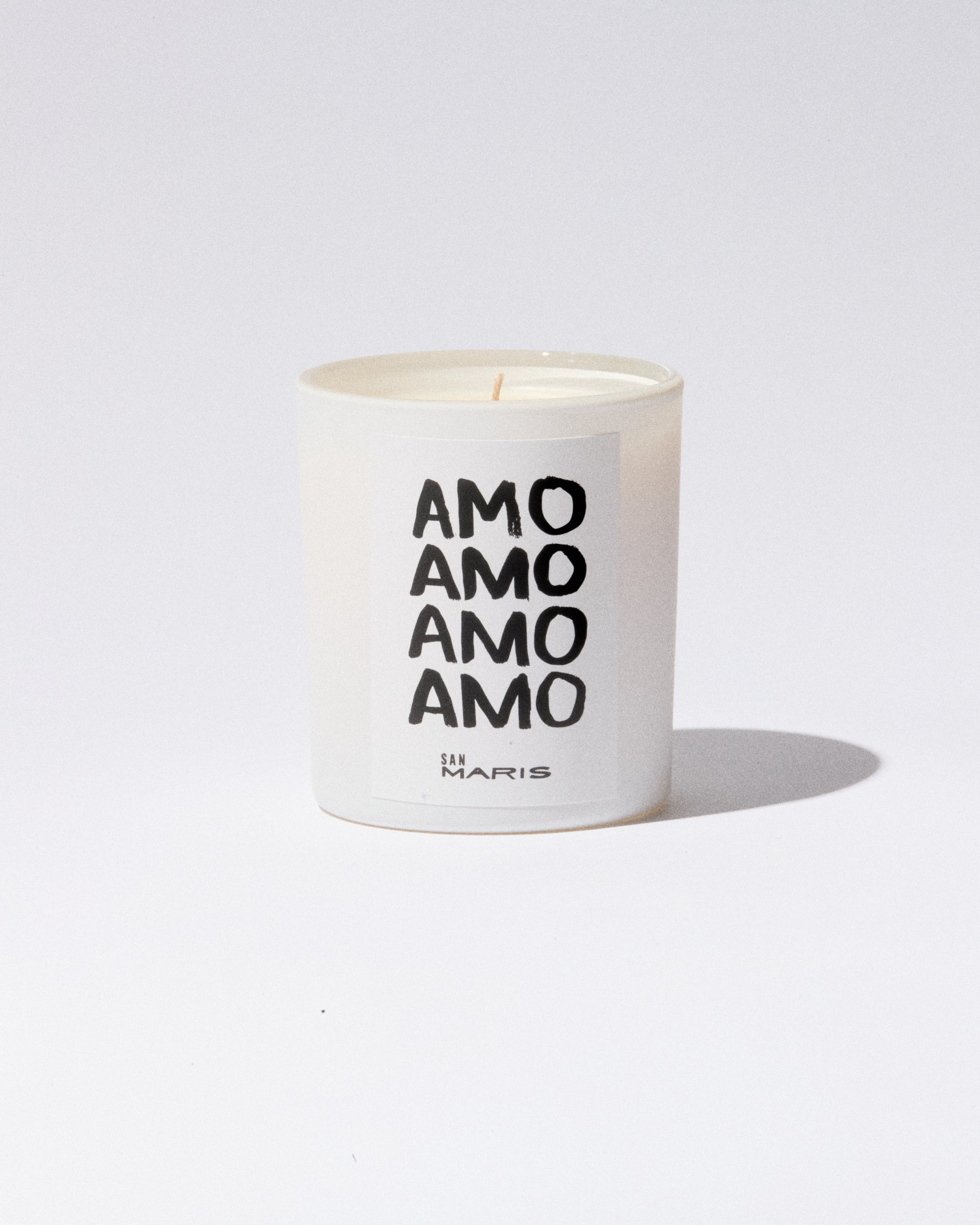 White candle with 'AMO AMO AMO AMO' text on a white background